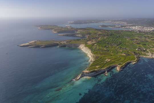 Aerial view of rugged Munxar Path meet the turquoise sea, creating a stunning contrast with the lush greenery inland, Marsaskala, Marsaskala, Malta.