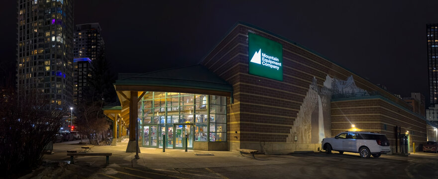 Calgary, Alberta, Canada. Feb 15, 2026. The exterior storefront of a Mountain Equipment Company retail location illuminated at night.