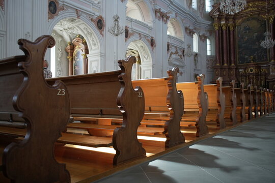 Interior view of the Jesuit Church in Lucerne, Switzerland, focusing on the wooden pews and detailed craftsmanship. 