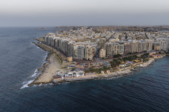 Aerial view of coastal buildings meet the azure sea, a blend of urban life and natural beauty, Sliema, Sliema, Malta.