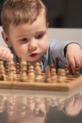 Baby studies chessboard with determination, reminding that champions are built from curiosity and patience.