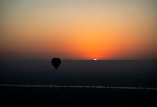 silueta de un globo aerostato con el sol saliendo por el horizonte en Luxor, Egipto