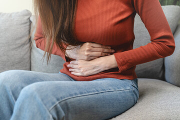 Fototapeta premium asian young woman intolerance hand in stomach ache, suffer from food poisoning, abdominal pain and colon problem