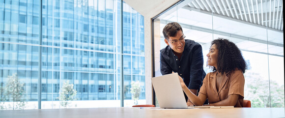 Business team two happy busy diverse young professional executives working together on computer at...