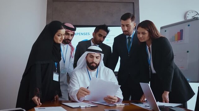 Western and emirati businesspeople in traditional arab attire participating in a conference with ceo, collaborating and taking notes in modern office environment