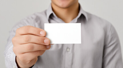 A man in a gray shirt holding out a blank white business card