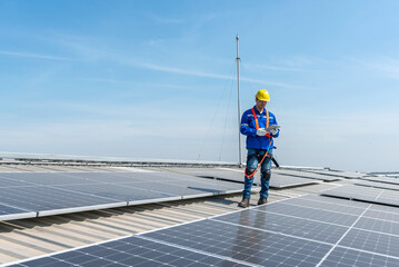 A solar panel installer walks across a roof inspecting the panels.