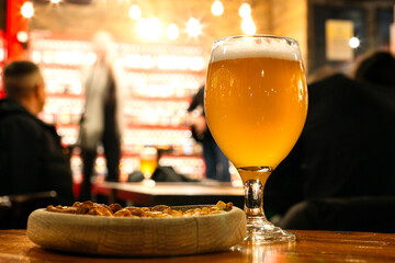A glass of beer with nuts on the table in the bar.