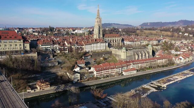 Bern, Switzerland: Aerial drone footage of a tram on the Kirchenfeld bridge over the Aar river  in Bern historic and city center with the cathedral in Switzerland on a sunny winter day. 