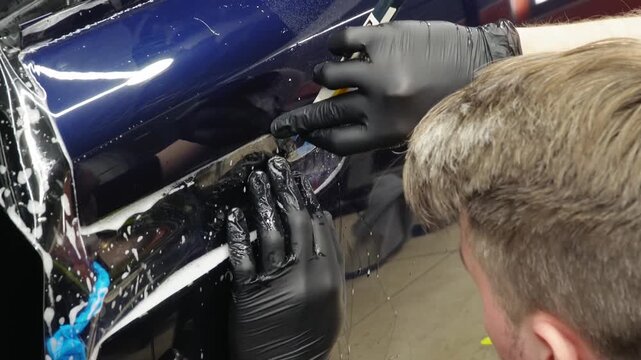 A car wrapping specialist applies a polyurethane film to the car. Selective focus. PPF protective film against chips and scratches. Anti-gravity protection. PFF is installed. Car wrapping close-up.