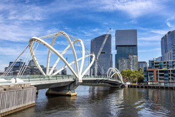 Obraz premium A view of the Yarra River and city architecture of Melbourne, Australia, with the Seafarers Bridge. Docklands and South Wharf in summer