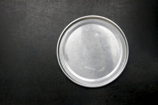 Aluminum tin plates on a dark table, flat lay view.