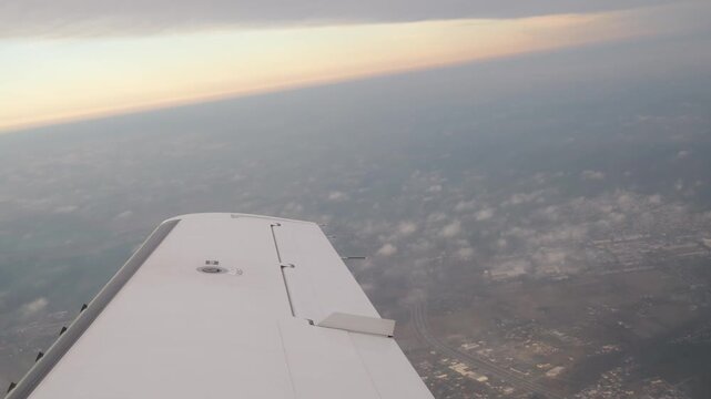 wing airplane flight white slicing through thin clouds above northern poland scattered towns fields visible below under soft fading horizon light from far view embraer e190 