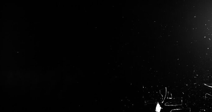 Super slow motion shattering glass filmed at 1000fps, side view with flying shards and dust isolated on black background. Perfect VFX overlay element for impact, crash or transition.