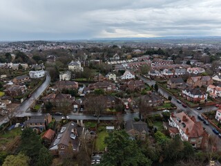 Fototapeta premium High‑resolution drone image showing town‑centre buildings, shops, roads and surrounding residential areas in Wirral, Merseyside. Ideal for editorial use, urban planning and community development.