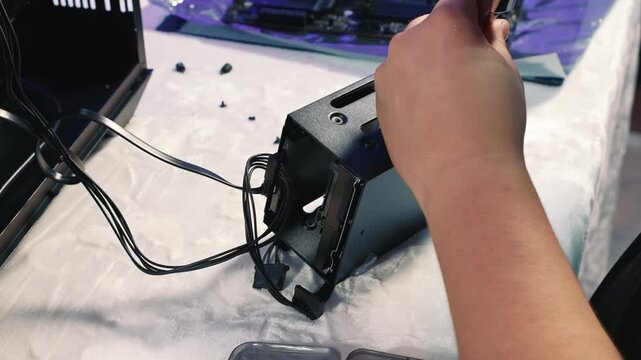 Securing installed hard drive in metal drive cage using screwdriver, preparing for mounting inside the case

