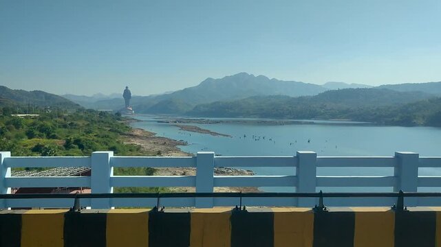 A scenic tracking shot of the Statue of Unity and Narmada River seen from a bridge, perfect for travel documentaries and Indian tourism content.