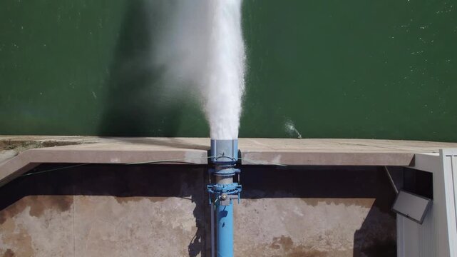 Hydropower station pumping water. Water outlet from dam wall. Howell Bunger valve in operation. Aerial view. Pressurized water outlet from dam wall. Water flowing from pumping in reservoir.