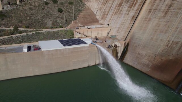 Hydropower station pumping water. Aerial view. Renewable energies. Howell Bunger valve in operation. Pressurized water outlet from dam wall. Water flowing from pumping in reservoir.
