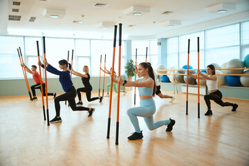 Fototapeta premium Group of people with gymnastic bars working out together