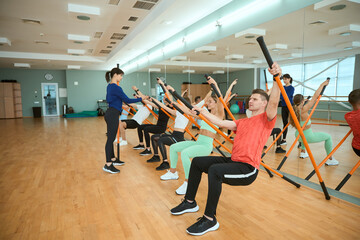 Obraz premium Sporty people is engaged fitness with an instructor using gymnastic sticks