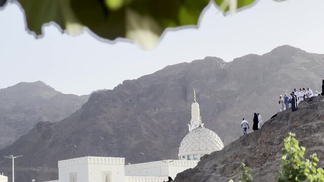 Experience the spiritual beauty of the Shuhada Mosque at the foot of Mount Uhud, Medina. This footage captures pilgrims exploring the historic site against backdrop of rugged Saudi Arabian mountains.