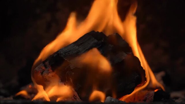 Close-up of burning charcoal with orange flames, promoting heat, energy and fire safety.