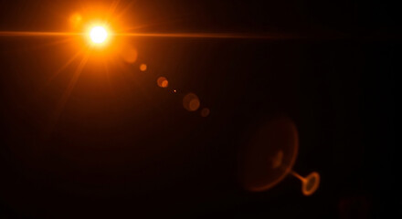 Fototapeta premium Bright Orange Lens Flare Effect with a Black Background and Bokeh Circles