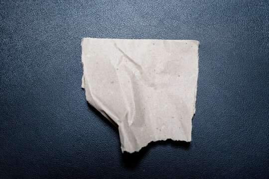 A crumpled piece of paper lies on a dark surface, symbolizing discarded ideas or notes. The wrinkled texture highlights the imperfections and transience of paper, conveying a sense of neglect or aban