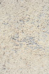 Obraz premium A rough beige and grey stucco wall with a gritty textured surface and natural shadows