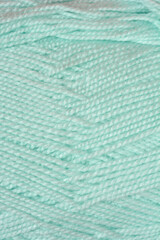 A macro shot showing the soft texture and twisted strands of light mint green wool yarn arranged in a diagonal pattern