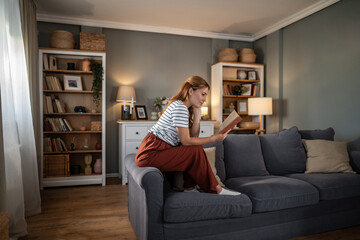 Obraz premium Woman reading book relaxing on sofa at home