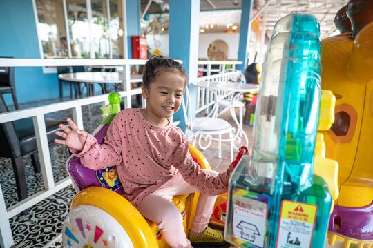 Little asian girl enjoy ride toy hourse outdoor playing