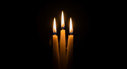 Fototapeta premium Intimate close-up of three cream tapered candles with golden flames on a black background, perfect for Valentine's Day, anniversaries, romantic evenings, home decor, spa ambiance,