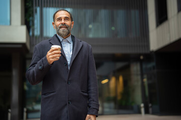 Mature businessman holding coffee cup and looking away