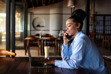 Happy freelancer enjoying a nutritious breakfast of smoothie and salad while working on a laptop