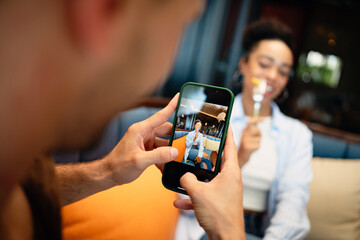 Diverse couple on a foodie date enjoys casual dining and a phone moment, sharing sunny vibes, drinks