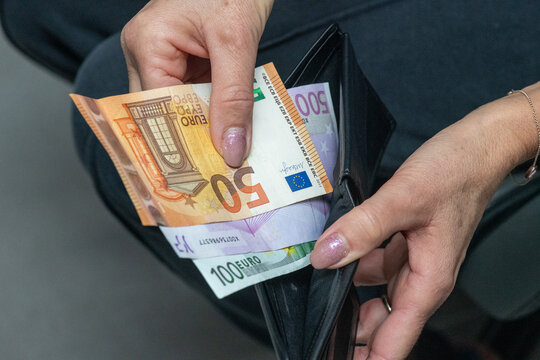Woman hand putting large euro banknotes into wallet concept of savings and finance