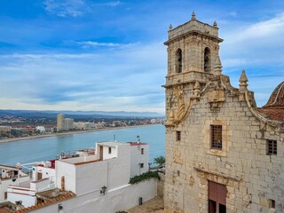 Coastal tower panorama. Carved facade frames seascape and skyline. Ancient bell structure overlooking harbor with scenic backdrop