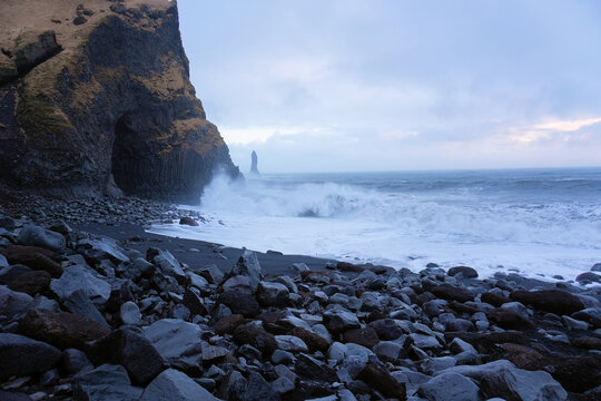 Der schwarze Strand Reynisfjara auf Island bei sehr starken Wellengang und stark bew&ouml;lkten Himmel	