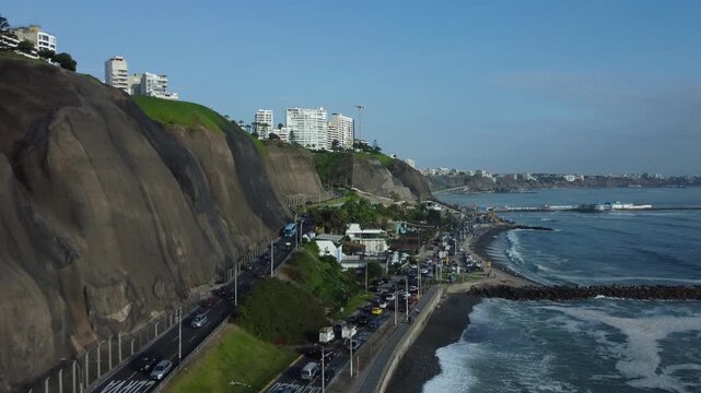 Aerial shot of "Costa Verde" highway. Drone flies forward then upwards and pans left showing a bridge over a road called "Bajada Balta". Located in Miraflores district of Lima, Peru.