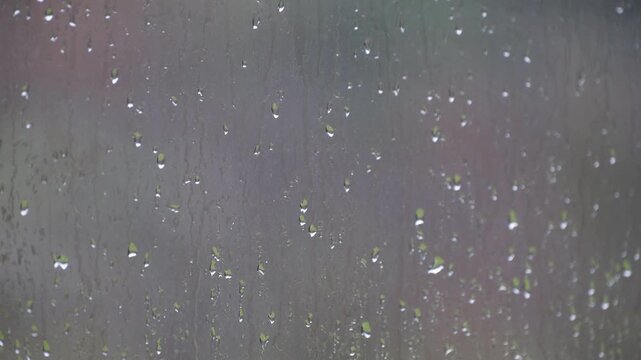 Rainwater flowing down a glass window during a storm, with a blurred background creating a sad mood