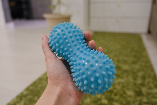 Close-up of a blue textured massage roller on the floor in a home interior. Fitness and recovery concept, self-massage equipment for home workout and muscle relaxation.