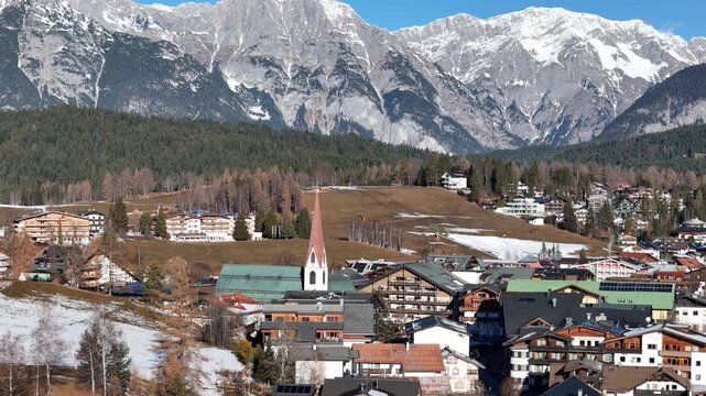 high perspective zooms heart town distinctive red steepled church green roofed buildings against backdrop rolling brown hills massive angle seefeld tirol austria center 