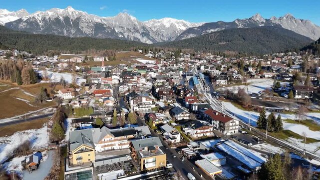 perspective sprawling alpine town seefeld diverse mix modern hotels traditional chalets framed by patches melting snow majestic jagged wide drone tirol austria 