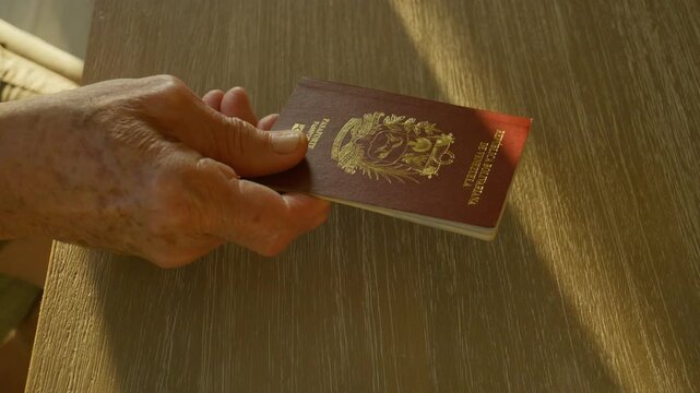 elderly male hand presents his Venezuelan passport onto a counter, another male hand takes it and replaces it with United States passport (slow slider, could use both or either shots) citizen ship
