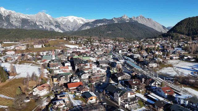 perspective sprawling alpine town seefeld diverse mix modern hotels traditional chalets framed by patches melting snow majestic jagged wide drone tirol austria 