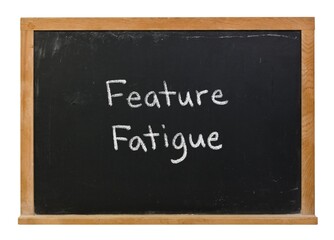 Obraz premium Feature Fatigue hand written in white chalk on a black chalkboard isolated on white in a wooden frame