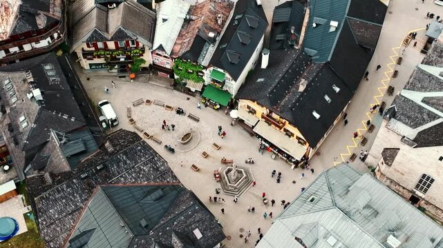Aerial drone footage of Hallstatt, Austria, showing the picturesque alpine village, lake shoreline, historic buildings, and surrounding mountains.