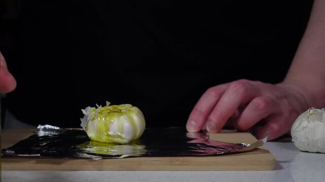 Drizzling oil on garlic and wrapping in foil for roasting